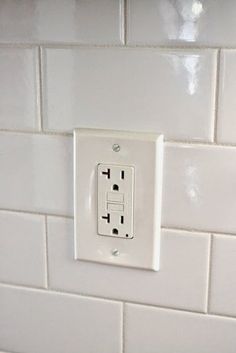 an electrical outlet on a white tiled wall