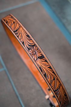 a wooden belt with intricate designs on the inside and outside, sitting on a tile floor