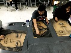 three people sitting at a table with some drawings on the floor next to each other