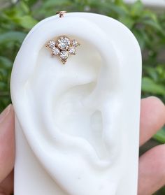 a close up of a person's hand holding a fake ear with a diamond ring on it