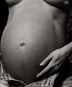 a black and white photo of a woman's belly with her hand on the stomach