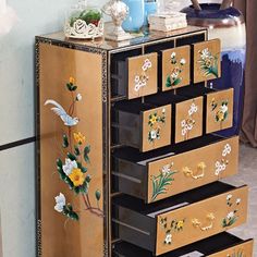 a wooden cabinet with drawers decorated with flowers and birds