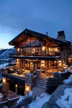 a large house with lots of windows and lights in the snow covered mountainside area