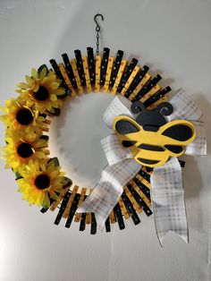 a sunflower wreath hanging on the wall with scissors attached to it and some flowers