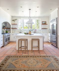 a kitchen with two stools in front of the counter and an area rug on the floor