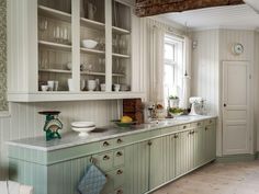 a kitchen filled with lots of green cabinets and counter top space next to a window