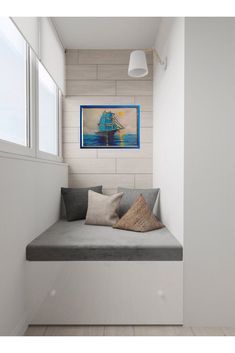 a white room with a gray couch and two windows on the wall, along with wooden flooring