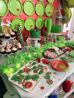 a table topped with lots of desserts and cupcakes covered in green frosting