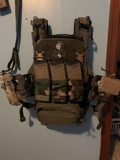 an army vest hanging on the wall with other items attached to it's back