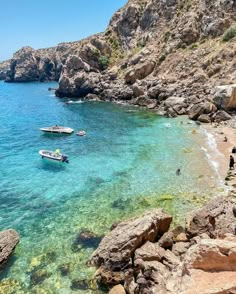 boats are in the clear blue water near some rocky coastlines and cliffs with people on them