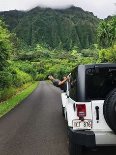 a jeep parked on the side of a road in front of a mountain with trees