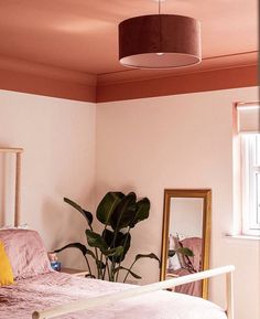 a bedroom with a bed, mirror and potted plant