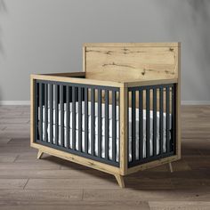 a wooden crib with white sheets and pillows on the bottom bed, in front of a gray wall