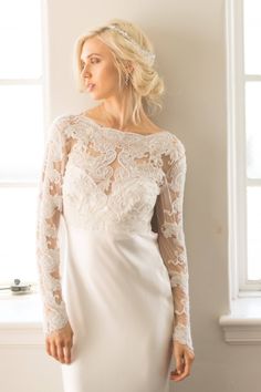 Our CAMERON COVER UP is a versatile addition to your bridal look. This long sleeve, sheer lace top features delicate hand-embroidered lace adorned with pearly seed beads and crystals. This sophisticated piece boasts a ballet neckline and a deep v-neck back, adding a touch of elegance. Perfect to wear as a wedding dress topper or as a crop top with a separate skirt.  *  Off White Hand Embroidered Scallop Lace with off white seed beads, sequins and crystals *  Made of Off White Stretch Mesh Base Fabric *  Available in XS, S, M, L, XL, See last image for Size Chart *  Hook & Eye Closure at Back *  Ships in 4-8 Weeks *  RUSH processing of 3-4 weeks is available for an additional $50 in dropdown options. *  This item is FINAL SALE as it is made to order. 🛒SHOP THE LOOK AND RELATED PRODUCTS * Wedding Dress Crop Top, Wedding Crop Top, Wedding Sleeves, Bridal Crop Top, Wedding Dress Topper, Crop Top Wedding Dress, Dress Crop Top, Long Sleeve Lace Top, Dress Topper