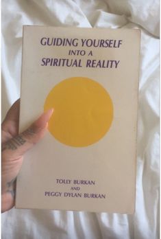 a person holding up a book with the title guiding yourself into a spiritual reality