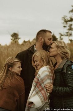 a group of people standing next to each other in front of tall grass and trees