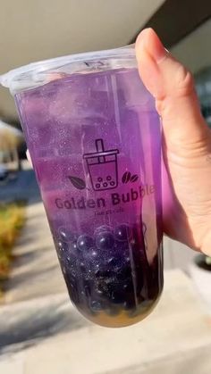 a person holding up a purple cup with blueberries in it