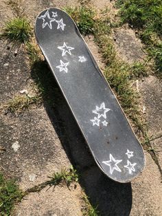 a skateboard laying on the ground with white stars painted on it's side