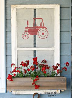 a window box with red flowers and a tractor drawn on it