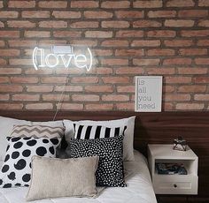 there is a bed with pillows on it and a neon sign above the headboard