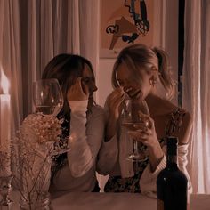 two women sitting at a table drinking wine