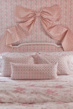 a bed with pink and white bedspread, pillows and headboard in a bedroom