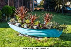 a blue boat shaped planter filled with succulents and plants in the garden