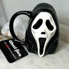 a black and white coffee mug with a ghost face on it next to a credit card