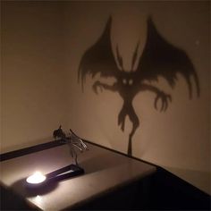 a shadow of a demon on the wall next to a desk with a pen and paper clip