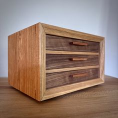 a wooden box with three drawers on top of it, sitting on a wood table