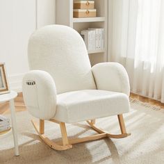 a white rocking chair sitting on top of a wooden floor next to a book shelf