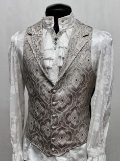 Note: These vests are very fitted. Check the size measurements below very carefully to find the size that will fit you best. A Victorian gentleman's vest with class. Great for formal occasions, can be worn under a suit jacket or by itself. Made in rich silver brocade fabric with an intricate design woven in with silver thread. With black satin lining inside and on the back. This vest has a very flattering tapered fit and ties in back with satin belting so it can be made tighter in the waist. Fas Victorian Outfit Men, Victorian Fashion Aesthetic, Aristocrat Vest, Victorian Mens Clothing, Victorian Vest, Victorian Gentleman, Victorian Wedding, Black Vest, Addams Family