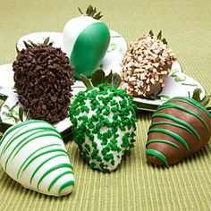 chocolate covered strawberries are arranged on plates with sprinkles and green decorations