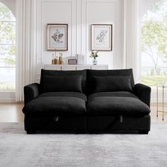 a black couch sitting in a living room next to two framed pictures on the wall