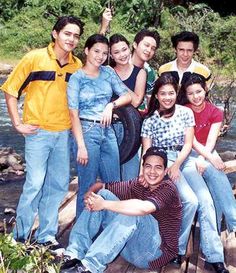 a group of people standing next to each other in front of a body of water