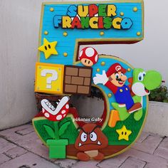 the number five is made out of cardboard and has mario bros characters on it,