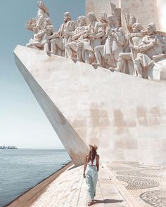 a woman standing in front of a monument with many statues on it's sides