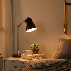 a table lamp sitting on top of a bed next to a cup and saucer