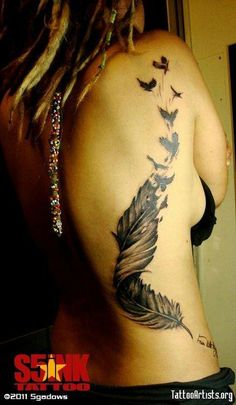 a woman's back with a feather tattoo on it