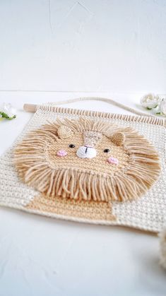 a crocheted lion rug on a white surface with flowers and yarn around it