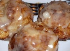 three glazed donuts on a plate with a fork