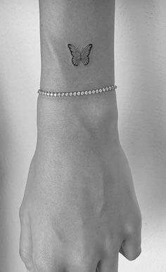 a woman's wrist with a small butterfly tattoo on the left side of her arm