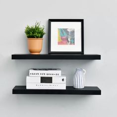 two black shelves with books and plants on them