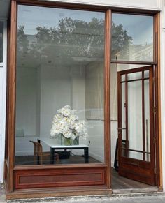 a vase filled with white flowers sitting on top of a table in front of a window