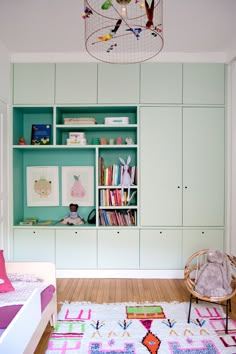 a child's room with green walls and white furniture, including a bed, bookshelf, toy chest and chair