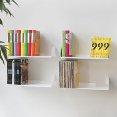 two white shelves with books and other items on them, one has a plant in it