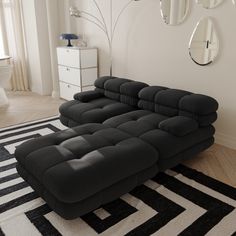 a large black couch sitting on top of a white and black rug in a living room