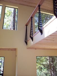 the inside of a house with windows and railings on each side, looking up at trees