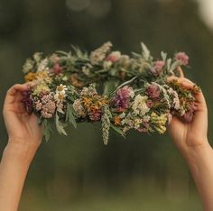 two hands holding flowers in the middle of each other's hands, with trees in the background