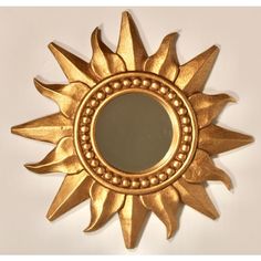 a gold sun shaped mirror on a white wall